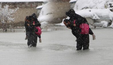 Evinin önünde biriken su nedeniyle çocuklarını sırtında taşıyor