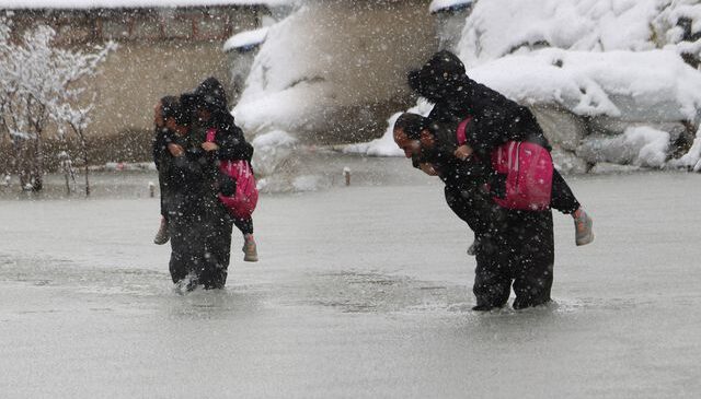 Evinin önünde biriken su nedeniyle çocuklarını sırtında taşıyor