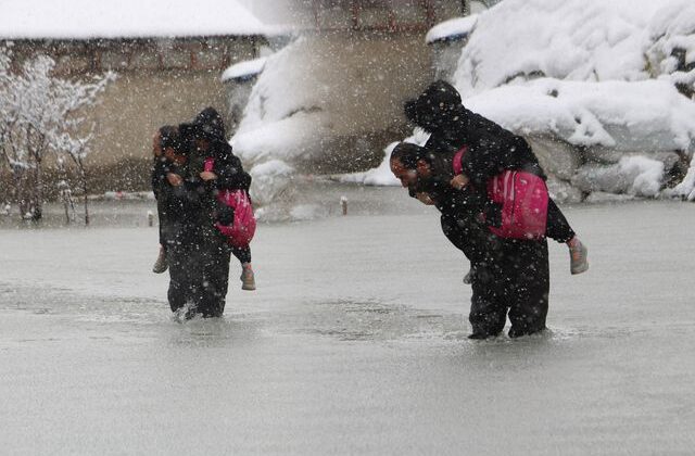 Evinin önünde biriken su nedeniyle çocuklarını sırtında taşıyor